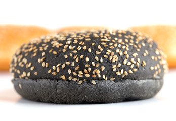 Burger buns on white background. A few buns cut in half close up on a white background. One black burger closeup.