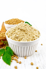 Flour soy with soybeans on wooden board