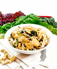 Funchoza with chard and cashew in bowl on board