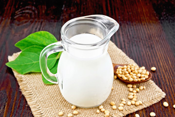 Milk soy in jug with beans on wooden board