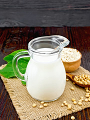 Milk soy in jug with flour and leaf on board