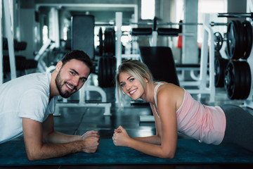 Fototapeta na wymiar Sporty couple planking exercise in fitness gym., Portrait of attractive young couple are practicing workout in training class., Caucasian man and woman in sportswear doing belly muscular exercising.