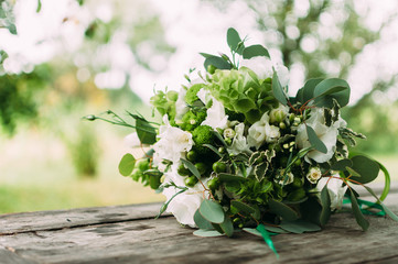 The wedding bouquet of white flowers on the wooden table.