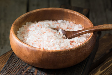 Sea pink salt in a wooden bowl on a wooden table. Rustic style