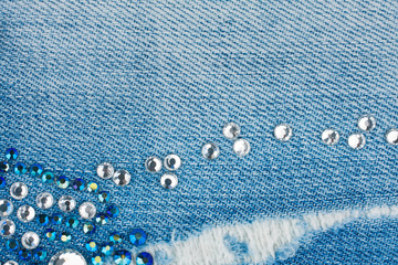 Light-blue torn denim with blue and silver rhinestones, background. - 244293362