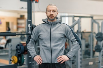 Fototapeta na wymiar Portrait of handsome sporty man in gym, cross fitness instructor looking at the camera