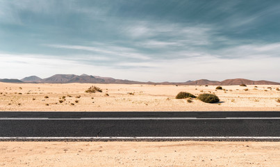 Fototapeta na wymiar Empty road through the desert dunes with copy space