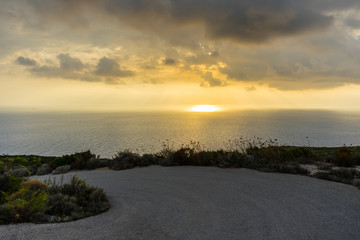 Greece, Zakynthos, Spectacular cloudscape sun breakthrough behind road bend and ocean