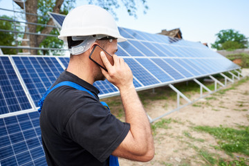 Back view of young engineer technician talking on cellphone standing in front of almost finished...