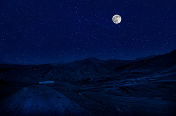 Mountain Road through the forest on a full moon night. Scenic night landscape of dark blue sky with moon. Azerbaijan