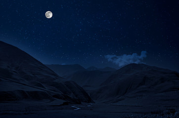 Mountain Road through the forest on a full moon night. Scenic night landscape of dark blue sky with moon. Azerbaijan