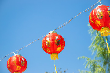 a collapsible paper lantern in bright colours, primarily red, used for decorative purposes, commonly painted with Chinese art.
