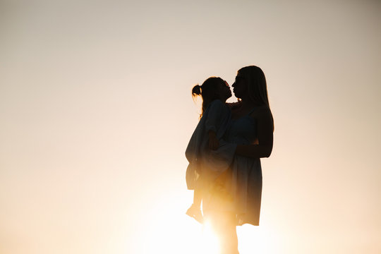 Silhouette of mother and little daughter. Summer sunset