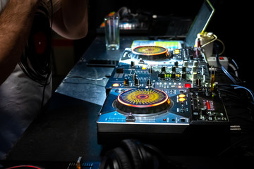 Obraz premium DJ music console, laptops and headphones in bright colors of light in night club bright red-blue background