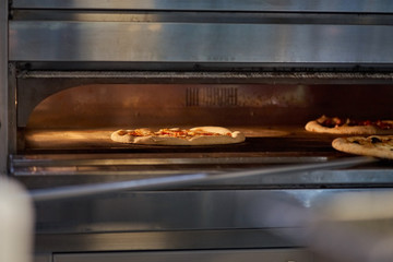 Cook putting Italian pizza to bake in oven. Preparation of pizza. selective focus, copy space.