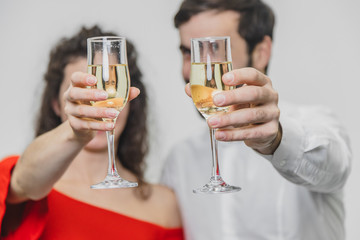 Loving young couple drinks champagne. On a white background. Dressed in red dress and white shirt.