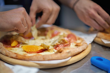 Chef making a parma or prosciutto ham Italian pizza in a close up view of his hands placing the meat