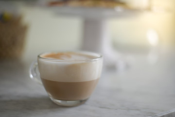 Foamy Cappuccino in a glass cup on a marble table