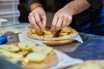 Cook in the kitchen putting the ingredients on the pizza. Pizza concept. Production and delivery of food.