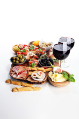Italian antipasti wine snacks set. Cheese variety, Mediterranean olives, pickles, Prosciutto di Parma, tomatoes, artichokes and wine in glasses