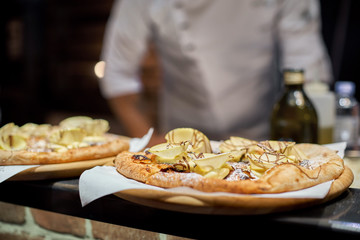 Cook in the kitchen putting the ingredients on the pizza. Pizza concept. Production and delivery of food.