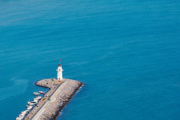 A lighthouse in harbor of Alanya, Turkey against a blue sea.