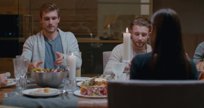 Friends or relatives having traditional thanksgiving dinner, passing the salad bowl. 4K UHD 60 FPS SLOW MOTION Blackmagic RAW