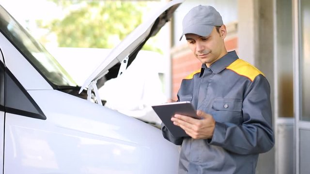 Mechainc using a tablet in front of a van