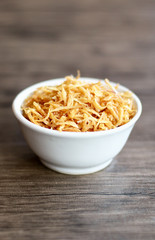 Fried red onion on wood background. Can used as topping on the side with the chicken, meat or fish dishes.