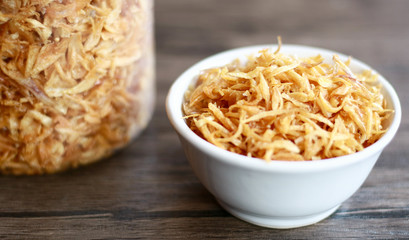 Fried red onion on wood background. Can used as topping on the side with the chicken, meat or fish dishes.