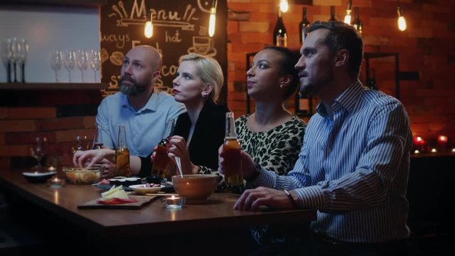Group of friends wathching tv in a cafe behind bar counter
