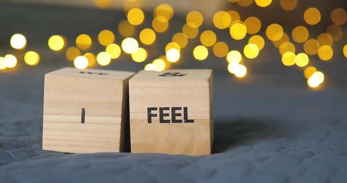 Male hands write phrase I Feel You from a wooden decorative cubes