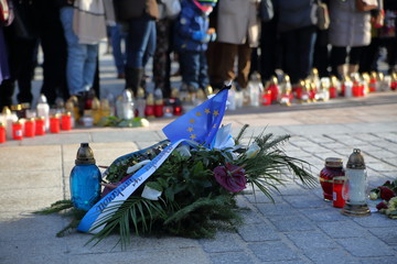 Wieniec kwiatów z flagą Unii Europejskiej i szarfą Rady Miasta Krakowa złożone na krakowskim Rynku po zamordowaniu prezydenta Gdańska Pawła Adamowicza, w tle rozmyte znicze, zgromadzeni ludzie - obrazy, fototapety, plakaty