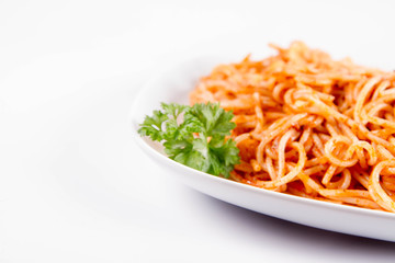 Spaghetti with pesto rosso decorated with parsley on a white background