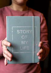 Woman hold notebook. Book notes for the Story of my life. Personal memoirs notes concept.