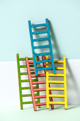 Multicoloured ladders on wall. Pastel tones. Concept for success and growth.