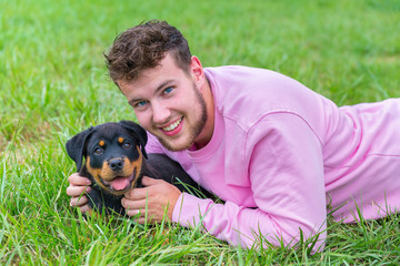 Dutch man lying with rottweiler puppy in grass