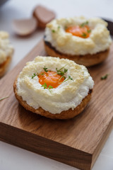 Bread with baked eggs Orsini on a wooden stand, selective focus
