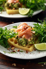 Potato waffles with avocado guacamole and smoked salmon for breakfast
