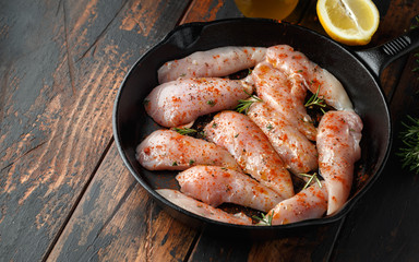 Raw chicken breast mini fillets in rastic cast iron skillet, frying pan with herbs and sea salt