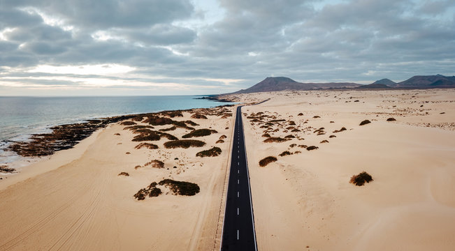 Aerial view of an empty road through the dunes at the sunrise with copy space