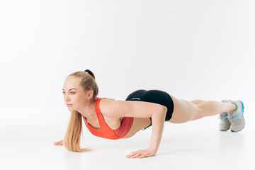 young woman is concentrated on push-up exercise on floor. isolated on white background. full length side view shot.hobby. effort