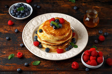 Homemade american pancakes with fresh blueberry, raspberries and honey. Healthy morning breakfast. rustic style