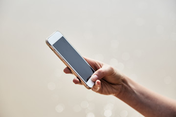 Mobile phone in female hand on the background of the beach and ocean