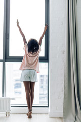 Fototapeta na wymiar sim woman standing near the window and stretching. back view photo. greeting new day. Good morning