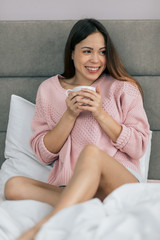 smiling good looking girl is drinking coffee and watching tv, good day. smiling girl on holiday