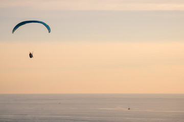 Skydiving of parachutist flying at sunset sky and sea background