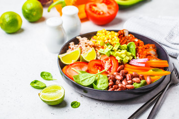 Mexican chicken burrito bowl with rice, beans, tomato, avocado,corn and spinach. Mexican cuisine food concept.