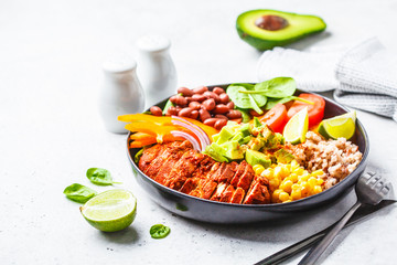 Mexican chicken burrito bowl with rice, beans, tomato, avocado,corn and spinach. Mexican cuisine food concept.