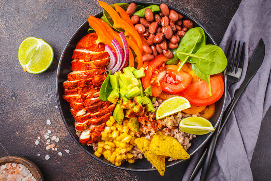 Mexican chicken burrito bowl with rice, beans, tomato, avocado,corn and spinach. Mexican cuisine food concept.